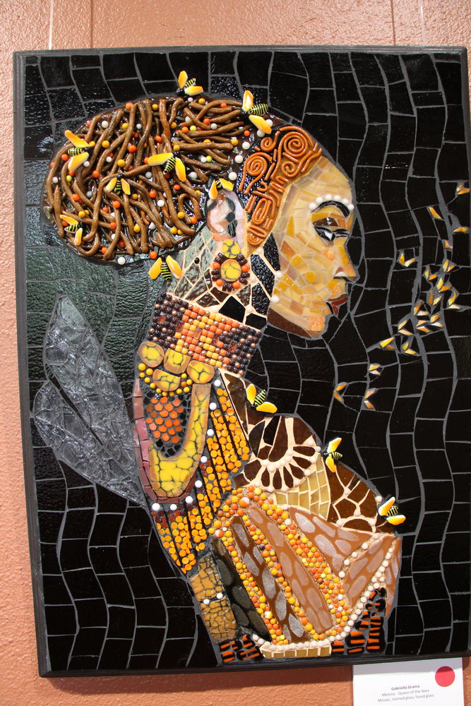 Regal and in repose, the queen gathers and guides her hive, but never reveals her inner machinations in this intricate portrayal. “Melona-Queen of Bees,” Gabriella Grama, mosaic, stained glass, fused glass.